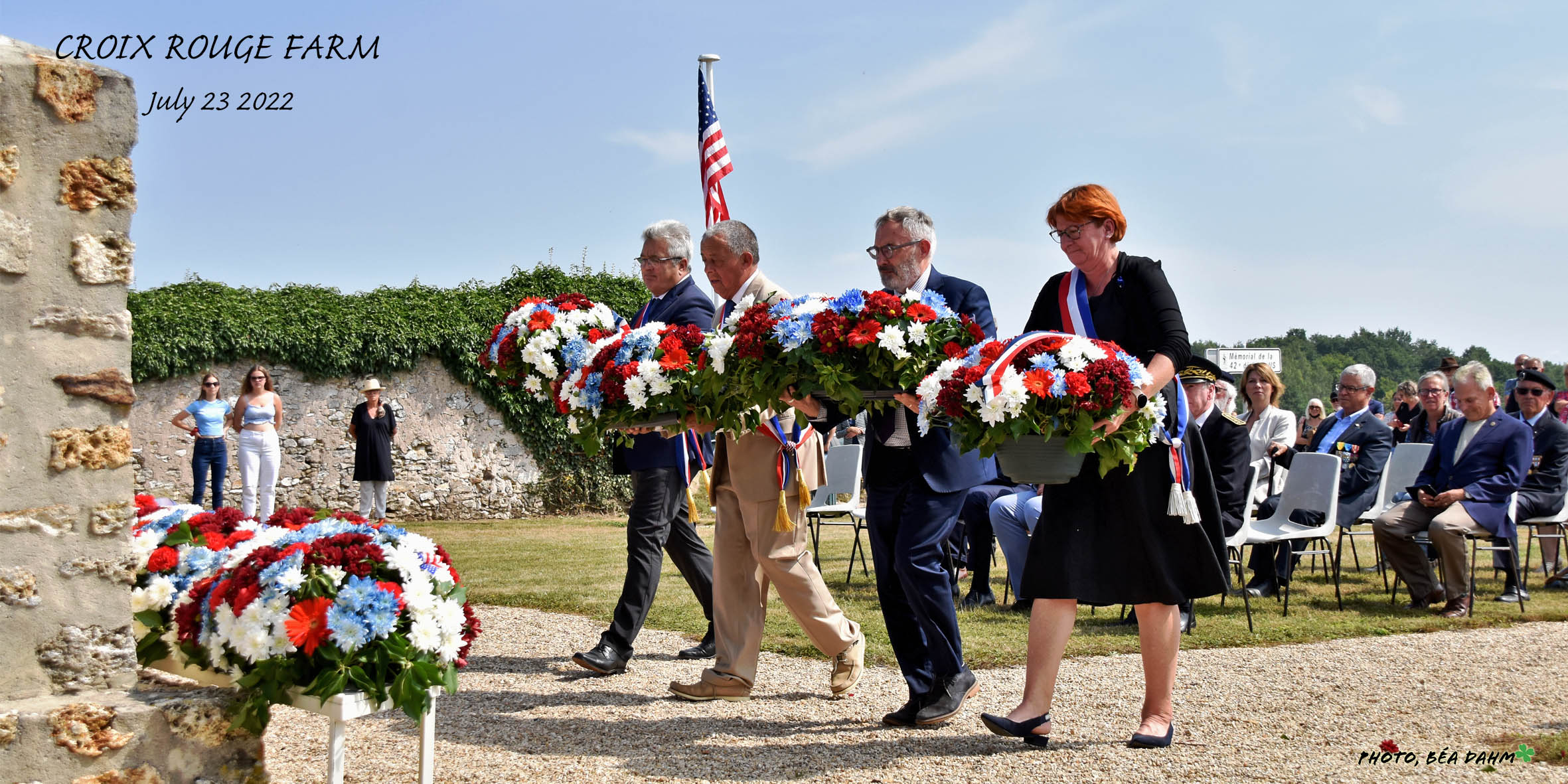 Four delegates holding wreaths walk toward a wall