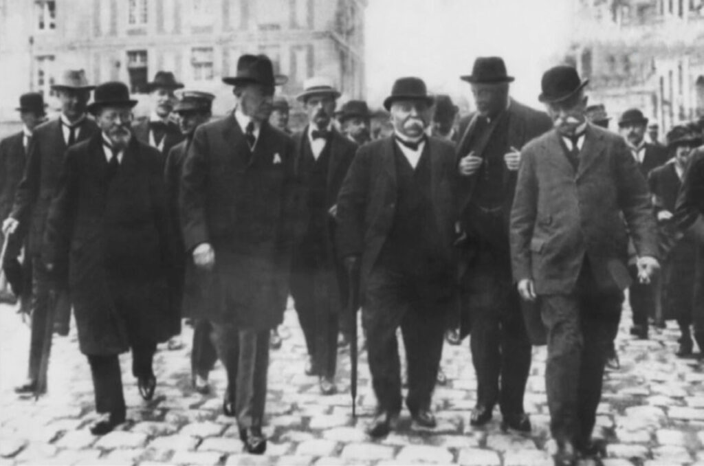 Wilson and other dignitaries walk down a cobblestone street