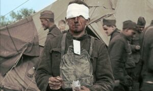 A wounded WWI soldier in front of a tent and other soldiers