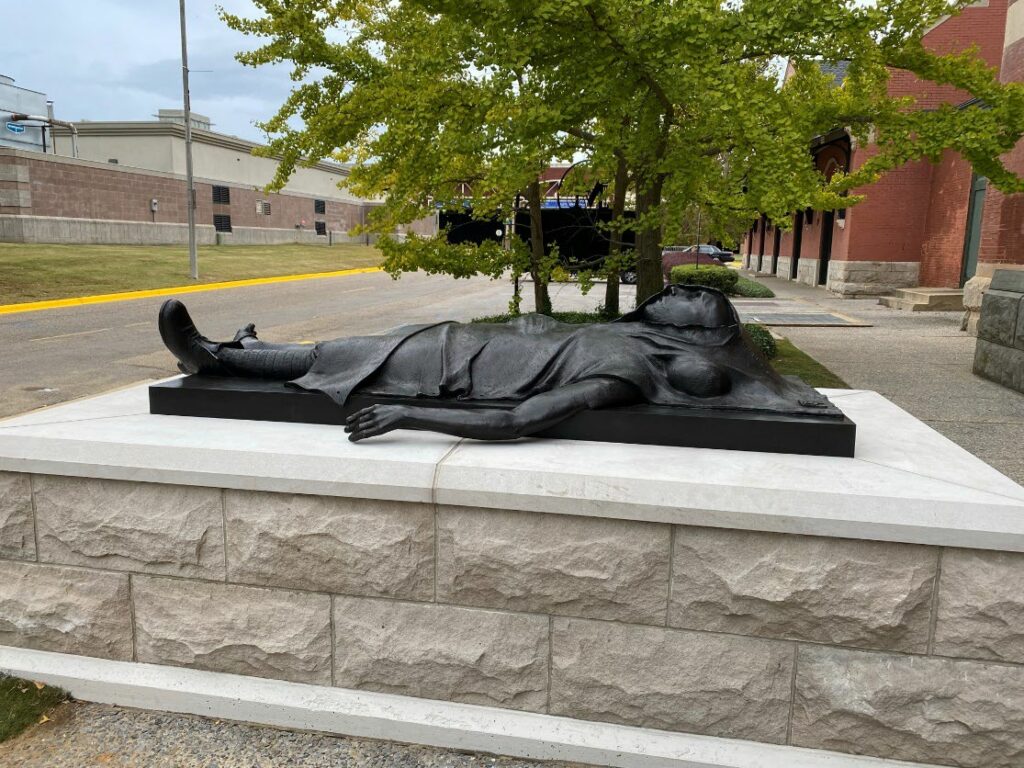 Side view of a statue of a dead returning soldier in front of a train station