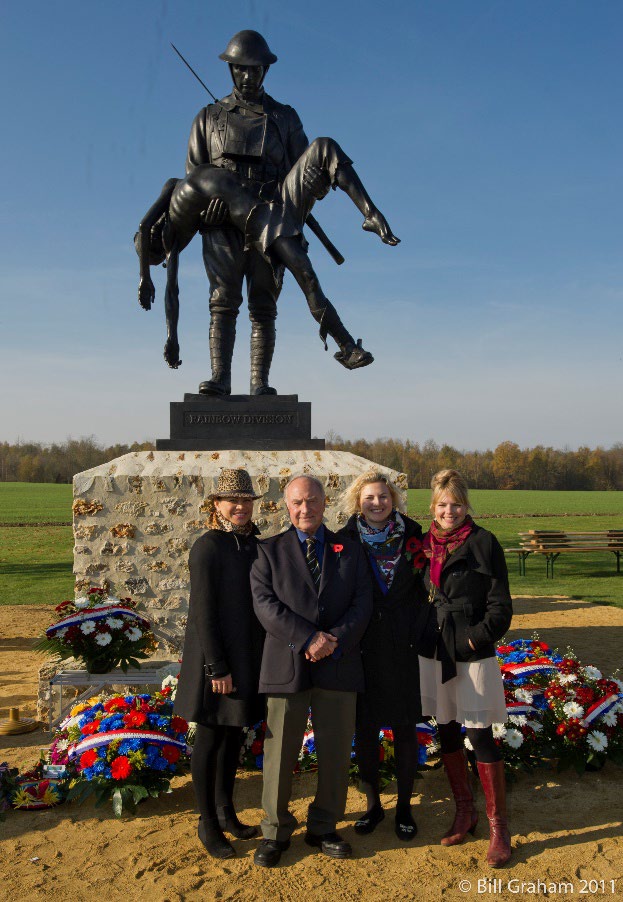 Four people stand in a sunny outdoor area in front of a statue