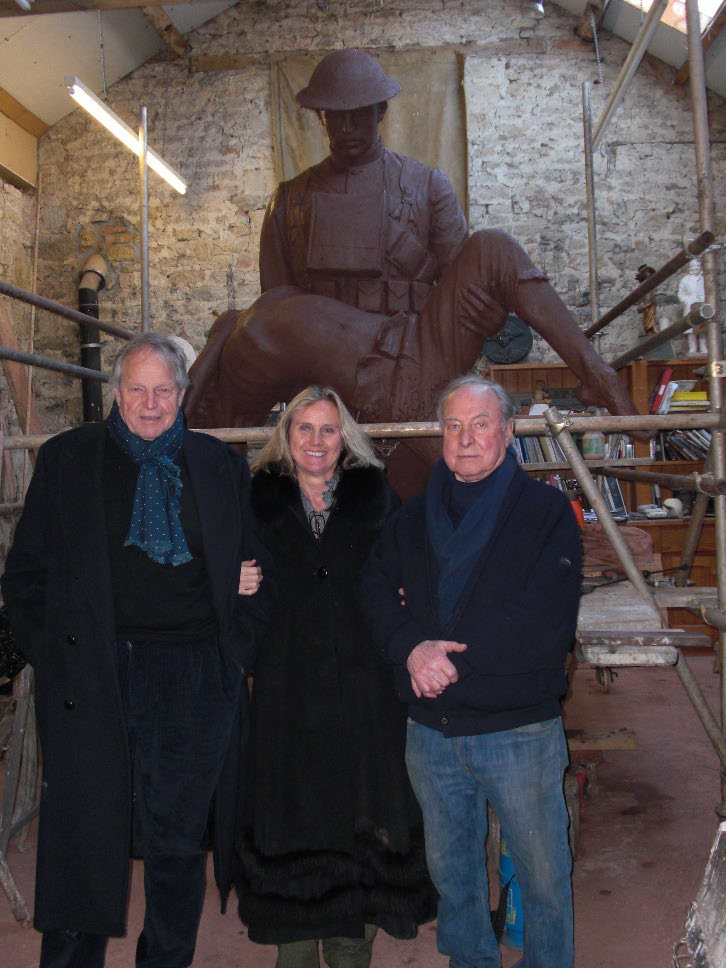 Three people in front of an in-progress statue