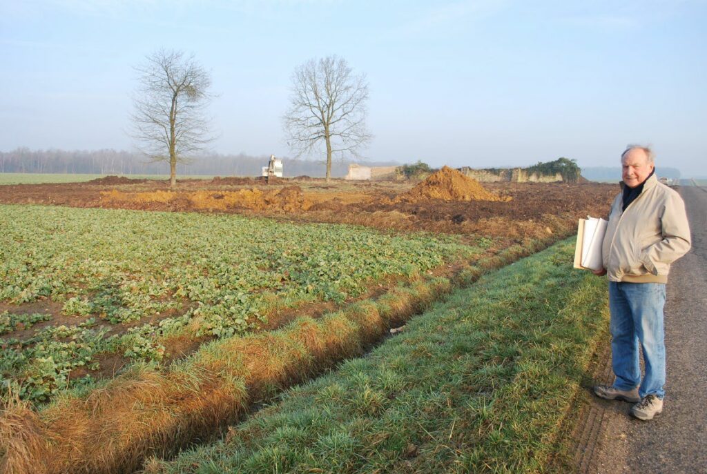 A man stands to the right of a cleared field