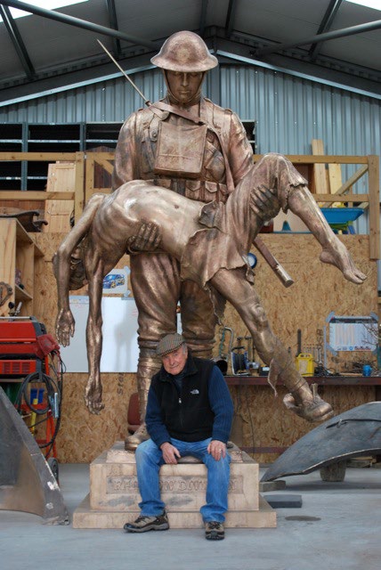 A man seated in front of a newly-cast statue