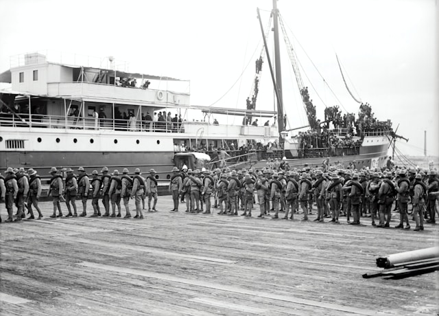 Soldiers embarking on a ship and waiting in several lines.